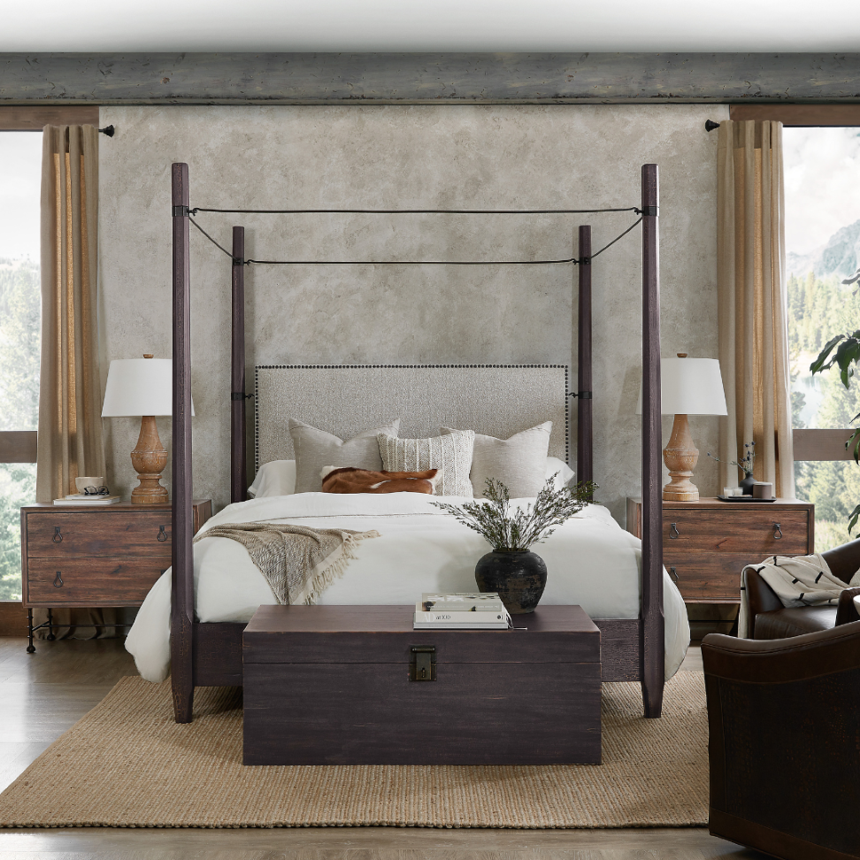 Luxury canopy bed with upholstered headboard, wood nightstands, and layered bedding in a warm Colorado mountain home bedroom.