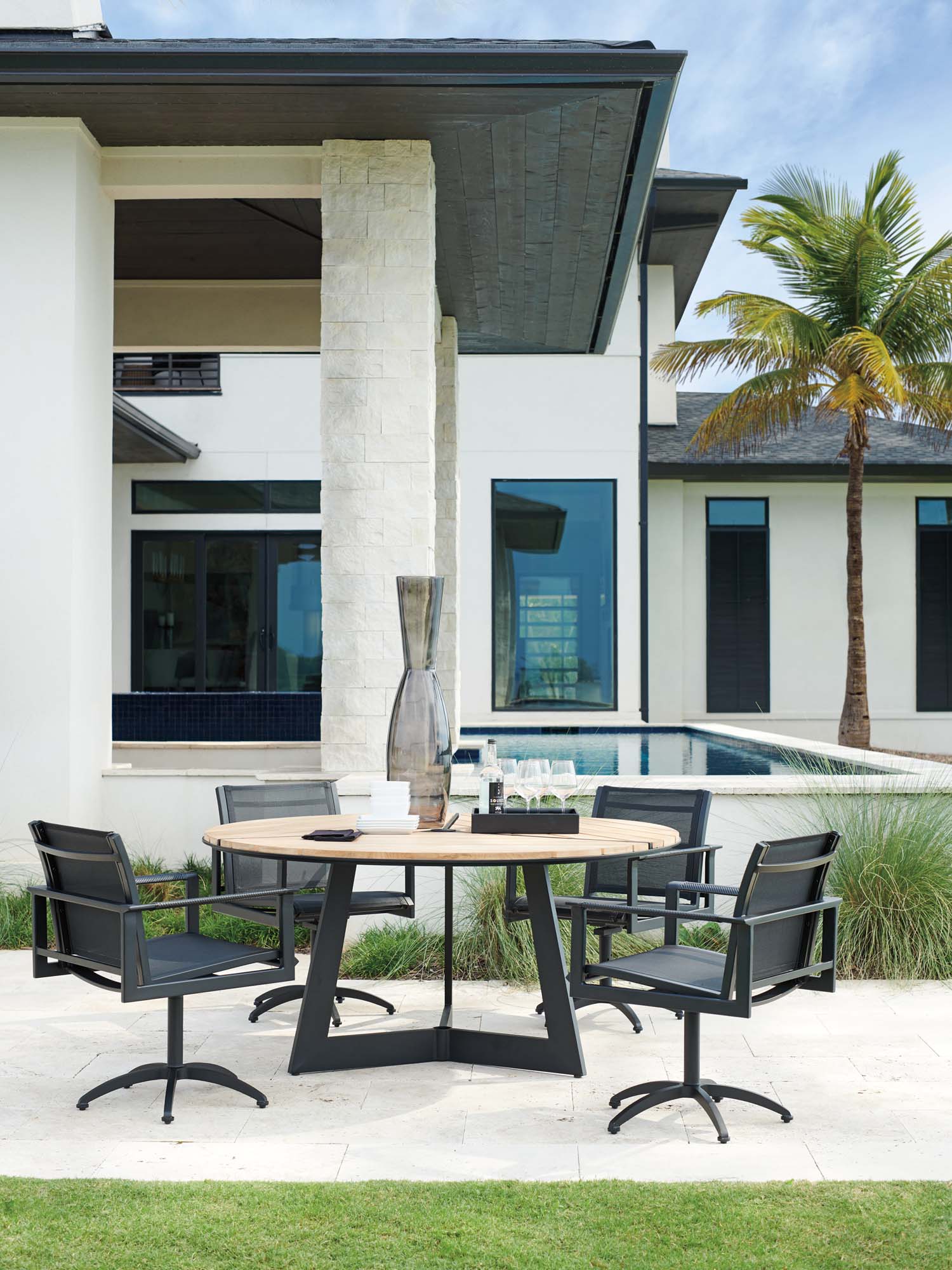Modern outdoor dining table and chairs beside a pool with contemporary patio styling.